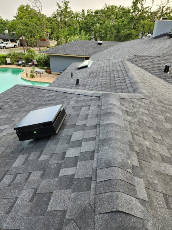 Dark grey architectural shingles on a multi-gable roof above a Katy, Texas backyard pool at dusk — Jerrys Roofing replacement